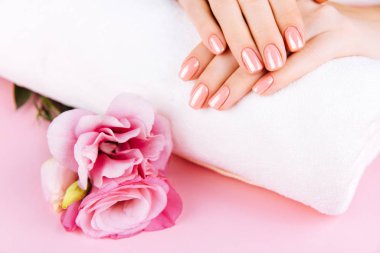 Güzel Kadın Elleri. Spa ve Manikür konsepti. Pembe manikürlü kadın elleri. Yumuşak cilt konsepti. Güzel tırnaklar. Bej arkaplanda.