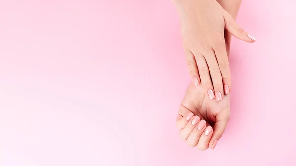 Όμορφη γυναίκα Χέρια σε ροζ backgrounda. Ιαματικά λουτρά και μανικιούρ. Γυναικεία χέρια με ροζ μανικιούρ. Απαλή έννοια περιποίησης δέρματος. Καρφιά ομορφιάς — Φωτογραφία Αρχείου