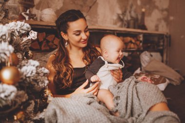 gülümseyen anne Noel ağacının yakınında güzel bebek ile oynarken.