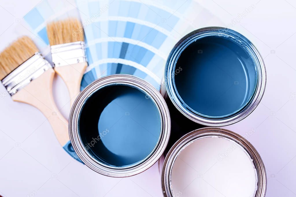 brushes and an open can with blue on plain gray background