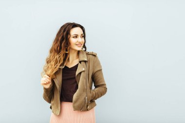 Güzel, genç, seksi, moda düşkünü, beyaz arka planda poz veren, moda tarzı ceketli, pembe tozlu etekli, şık, siyah saçlı, hippi bir kız. Beyaz arka planda, beyaz değil.