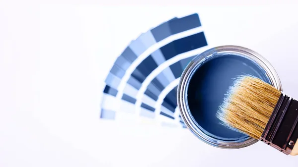 Pinceles colocados en la parte superior de la lata llenos de pintura azul. Clásico color azul del año 2020 . —  Fotos de Stock
