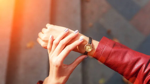Street style fashion details. close up, young fashion blogger wearing a jacket and a analog wrist watch. stylish woman checking the time on her watch. autumn fall season