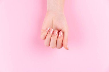 Güzel Kadın Elleri. Spa ve Manikür konsepti. Pembe manikürlü kadın elleri. Yumuşak cilt konsepti. Güzel tırnaklar. Bej arkaplanda