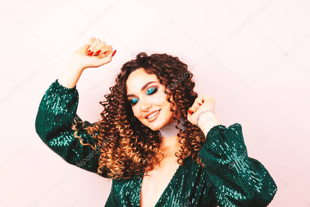 Party and holidays concept. Glamour woman in luxury glitter sequins dress dancing and having fun. Hollywood make up, wavy hairstyle. White background. fashion shiny green dress