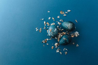 Üzerinde grup altın ve mavi benekli paskalya yumurtaları olan çerçeve metin için fotokopi alanı ile. Mavi arka planda. Mutlu Paskalyalar