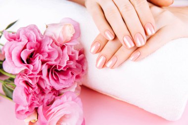 Güzel Kadın Elleri ve taze bir Eustoma. Spa ve Manikür konsepti. Pembe manikürlü kadın elleri. Yumuşak cilt konsepti. Güzel tırnaklar. Bej arkaplanda