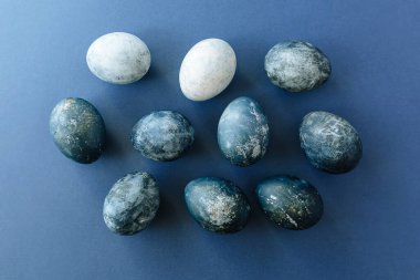 Mavi arka planda bıldırcın yumurtaları ve tüyleri olan güzel bir grup ombre mavi paskalya yumurtası. Paskalya konsepti. Sınır yumurtaları. Metin için alanı kopyala.