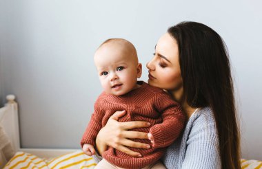 Küçük bir kız bebek gülümsedi ve annesiyle yatakta oynadı.