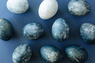 Mavi arka planda bıldırcın yumurtaları ve tüyleri olan güzel bir grup ombre mavi paskalya yumurtası. Paskalya konsepti. Sınır yumurtaları. Metin için alanı kopyala.