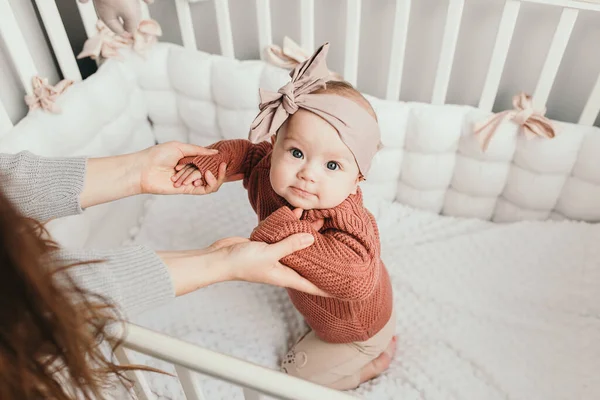 Hermosa niña en la cama con su mamá, luz interior elegante. tratando de estar de pie . —  Fotos de Stock