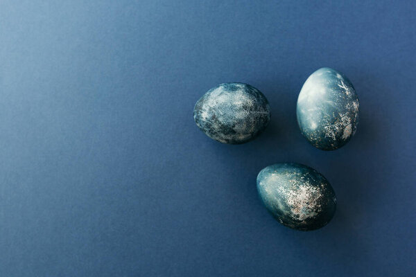 Beautiful group ombre blue Easter eggs with quail eggs and feathers on a blue background. Easter concept. Border eggs. Copy space for text.