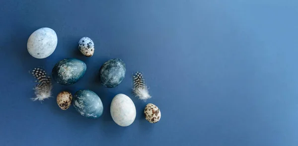美しいグループは青い背景にウズラの卵と羽を持つ青いイースターの卵を爆撃します。イースターのコンセプト。国境の卵テキストのコピースペース. — ストック写真