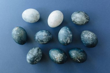 Mavi arka planda bıldırcın yumurtaları ve tüyleri olan güzel bir grup ombre mavi paskalya yumurtası. Paskalya konsepti. Sınır yumurtaları. Metin için alanı kopyala.