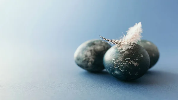 Huevo de Pascua wirh pluma sobre fondo azul con espacio vacío. Tarjeta de Pascua — Foto de Stock