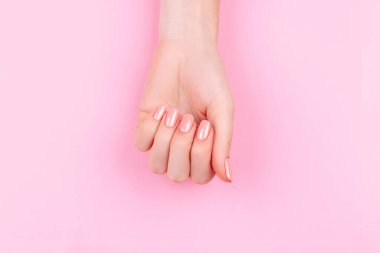 Güzel Kadın Elleri ve taze bir Eustoma. Spa ve Manikür konsepti. Pembe manikürlü kadın elleri. Yumuşak cilt konsepti. Güzel tırnaklar. Bej arkaplanda