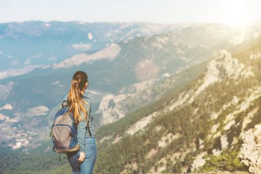 Genç ve güzel bir kız baharda ya da sonbaharda dağlarda tek başına seyahat eder, uzaklığa bakar ve doğanın, kayaların ve yeşil ormanların tadını çıkarır, manzaranın tadını çıkarır. Sırt çantası ve spor kıyafetleri.