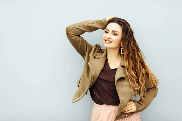 Linda, sexy, menina de cabelo marrom na moda em uma jaqueta marrom e saia rosa posando no fundo branco — Fotografia de Stock