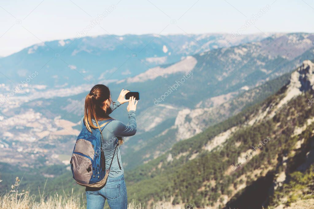 Tourist girl making a photo shoot of mountain.