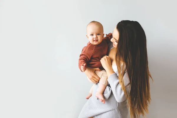 Happy mother holding up her baby girl. Young beautiful mother holds her baby and cuddles, motherhood concept. — Stock Photo, Image