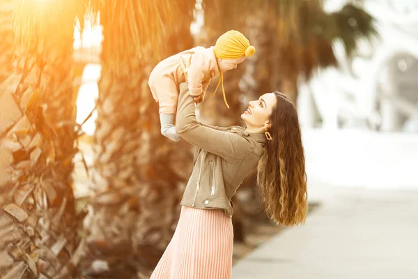 Increíblemente hermosa madre sosteniendo en sus brazos a su hija y besándose afuera. Aspecto elegante de moda —  Fotos de Stock