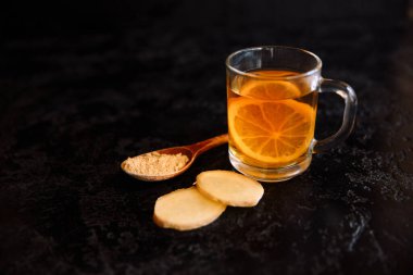 Zencefil kökleri ve koyu arkaplanda bir kaşık zencefil karışımı.