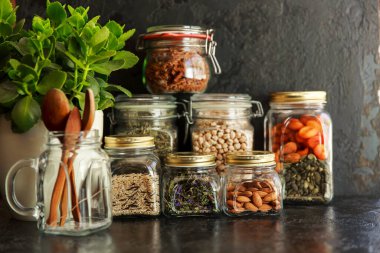 Yemek takımı. Çiğ tahıl, makarna, inleme, organik baklagiller ve cam kavanozlarda faydalı tohumlar..