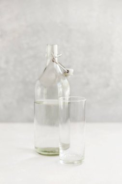 Hafif arka planda cam su şişesi, limonlu bir bardak su, sağlıklı bir yaşam tarzı ve sağlıklı bir diyet, ekolojik depolama konsepti.,