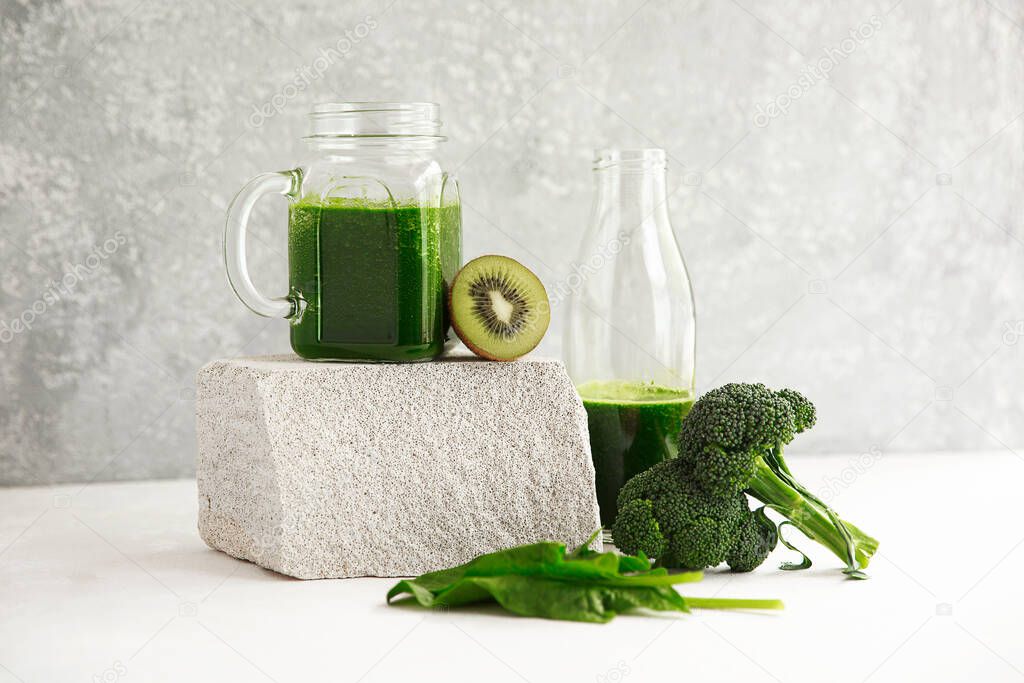 Green smoothie from broccoli, spinach, kiwi and banana on a light background. Eco concept. Healthy green smoothie and ingredients on white - superfoods, detox, diet, health, vegetarian food concept