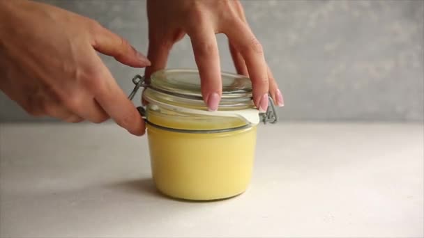 Ghee ou manteiga derretida em um frasco em mesa de madeira. obter uma colher de prata de uma lata. — Vídeo de Stock