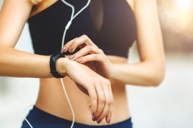 Dışarıdaki eğitimden sonra akıllı saati kontrol eden kadın..