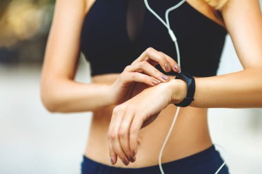 Dışarıdaki eğitimden sonra akıllı saati kontrol eden kadın..