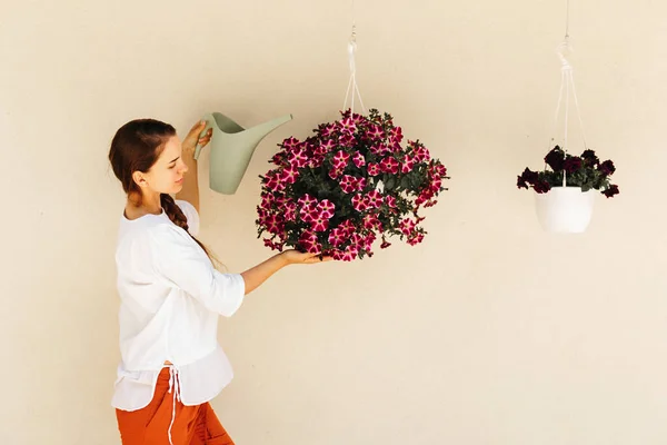 Lovely housewife with flower in pot and watering can. — Stock Photo, Image