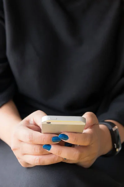 Gros plan des mains tenant le téléphone intelligent sur les vêtements noirs backgroun — Photo