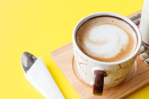 Hot cup of cappuccino coffee on yellow table background — Stock Photo, Image
