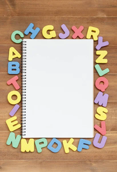 Espuma letras do alfabeto inglês com caderno de página em branco aberto em w — Fotografia de Stock