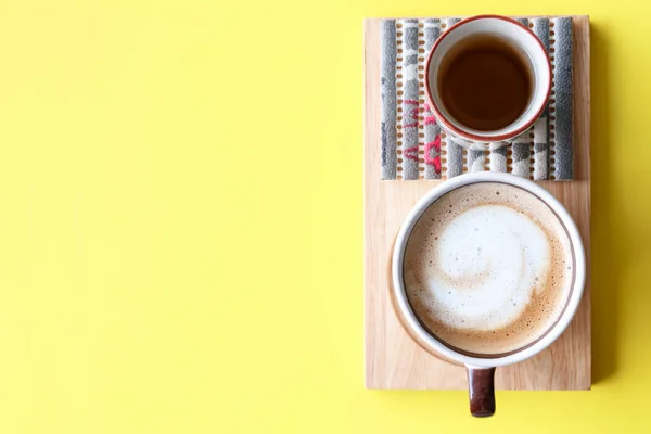 Hot cup of cappuccino coffee on yellow table background — Stock Photo, Image