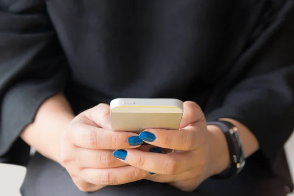 Gros plan des mains femme tenant téléphone intelligent sur des vêtements noirs bac — Photo