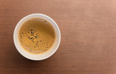 Kahverengi ahşap masada siyah kahve fincanının en üst görüntüsü.