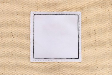 Kahverengi tuval kumaş arka planında boş beyaz deri etiket