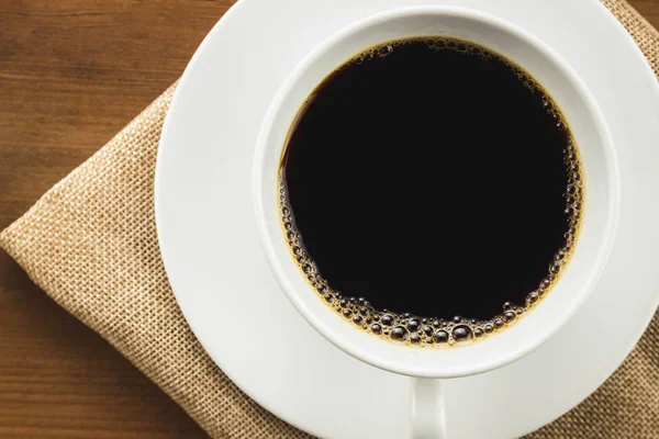Zbliżenie filiżanka czarnej kawy na drewnianym stole — Zdjęcie stockowe