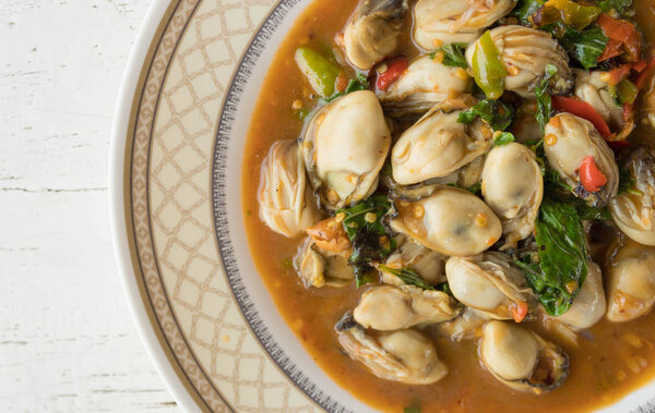 Перемешать жареную устрицу с листьями базилика на блюде
