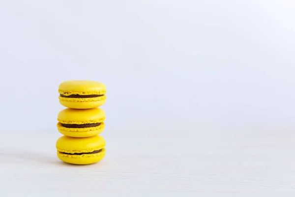 Tres macarrones franceses amarillos sobre una mesa de madera. Macarrones de plátano con crema de chocolate . — Foto de Stock