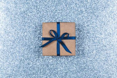 Işıl ışıl açık mavi arka planda mavi fiyonklu el işi hediye kutusu. Tatil kavramı. 