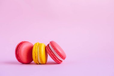 Pembe arka planda üç lezzetli Fransız badem kurabiyesi. Pembe ve sarı badem kurabiyeleri.