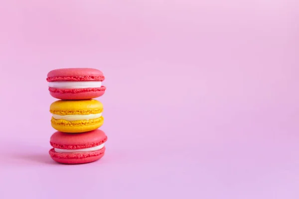 Tres sabrosos macarrones franceses sobre fondo rosa. Macarrones rosados y amarillos . — Foto de Stock