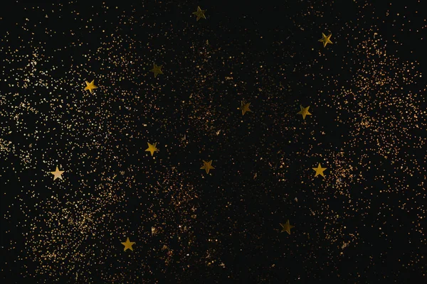 Golden sparkles and stars on black backdrop. Holiday concept.