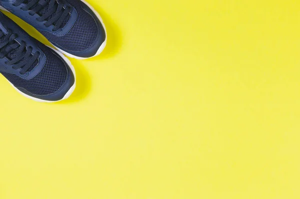 Zapatillas clásicas azules sobre fondo amarillo. Concepto para un estilo de vida saludable y entrenamiento diario . — Foto de Stock