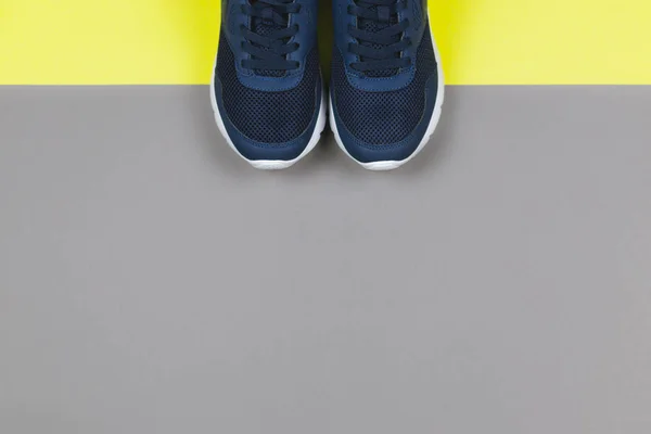 Classiche sneakers blu sullo sfondo giallo e grigio. Concetto per uno stile di vita sano e allenamento quotidiano . — Foto Stock