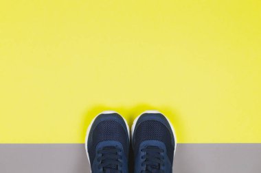 Sarı ve gri arka planda klasik mavi spor ayakkabılar. Sağlıklı yaşam tarzı ve günlük eğitim kavramı. 
